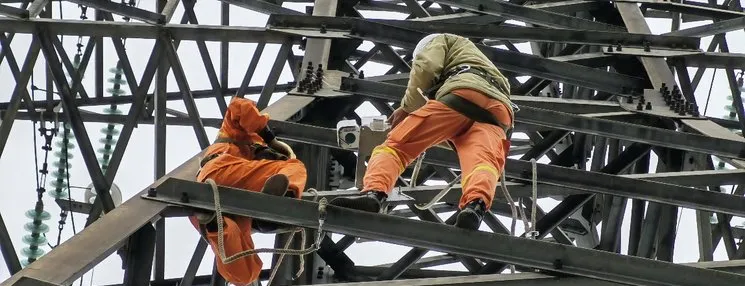 Technicians installing monitoring equipment on a transmission tower